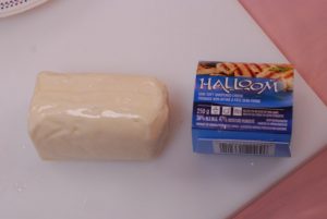A block of halloumi cheese on a cheese board. This cheese is an example of predominantly rennet-coagulated fresh cheese.